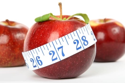 A measuring tape wrapped around a red apple