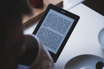 A person enjoying a quiet, cozy moment, sipping from a warm mug of coffee while reading an ebook