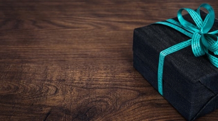 A neatly packed black gift box resting on a wooden desk