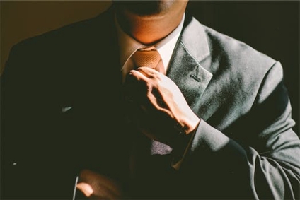 A young professional in black business attire, fixing tie
