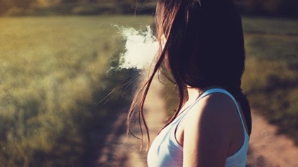 A woman exhales thick vape smoke