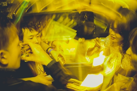 A blurry, yellow-tinted image of a party where people are drinking