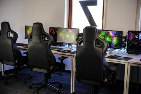 A gaming room with gaming chairs facing modern PCs with gaming equipment