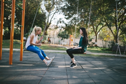 Girls seated across from one another on swings, engaged in conversation
