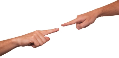 A close-up of two hands, each with the index finger pointed out, aimed directly at the other